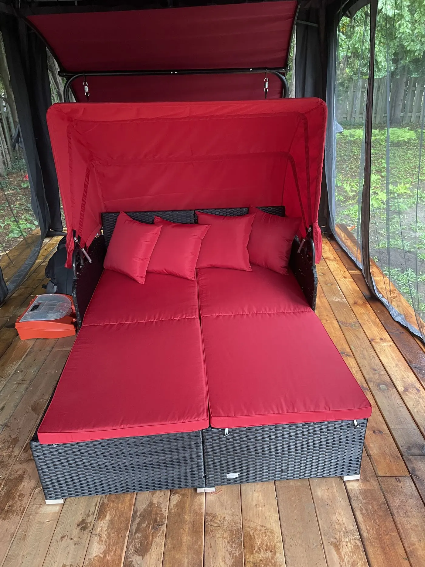 Causeuse extérieure rouge avec toit, montée sur une terrasse